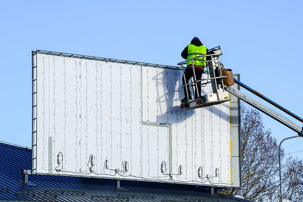 Hombre instalando un rótulo del curso PRL para instaladores