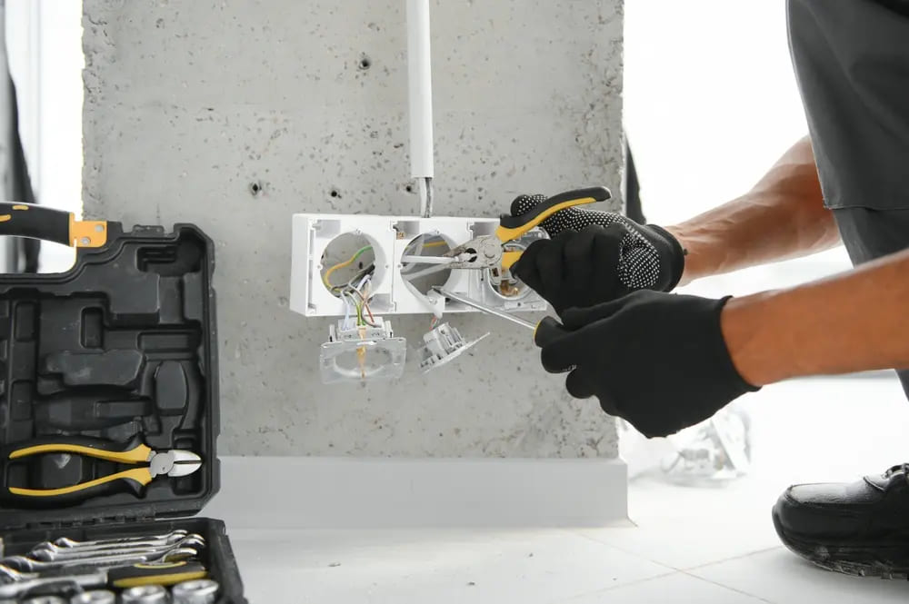 electricista usando guantes dieléctricos para cambiar un enchufe