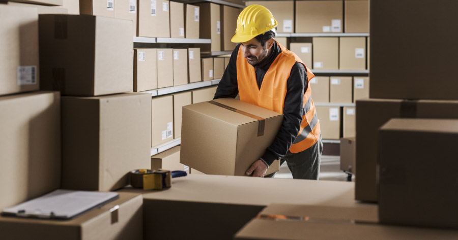 Trabajador levanta una caja mal como riesgo ergonómico