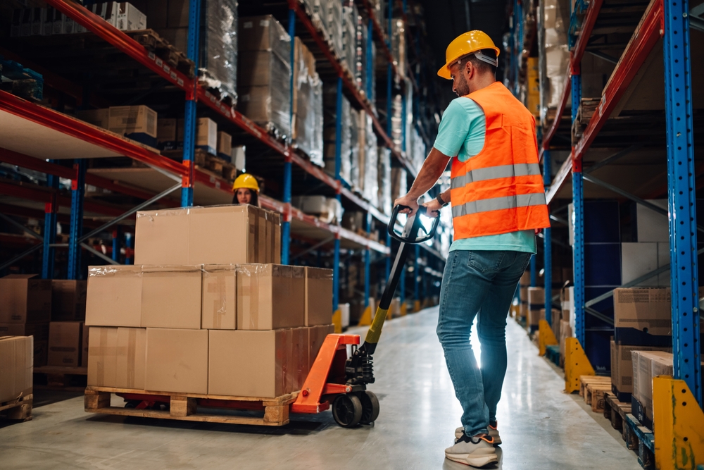 operario de almacén usando una transpaleta manual